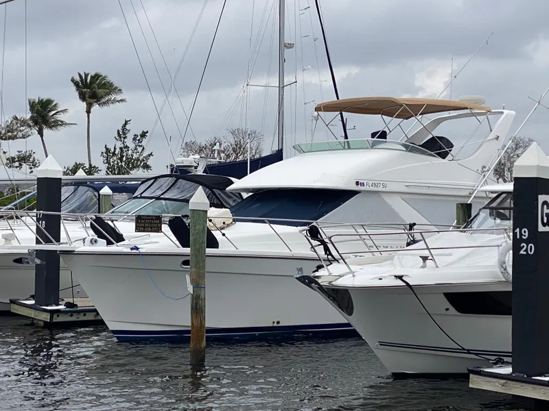 Slide: The Image of 2001 Bayliner 3988 yacht docked at marina, surrounded by other boats, under cloudy skies. - 2