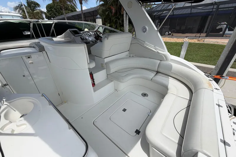 Slide: The Image of 2001 Cruisers Yachts 3672 Express cockpit with white seating and helm, docked outdoors. - 9