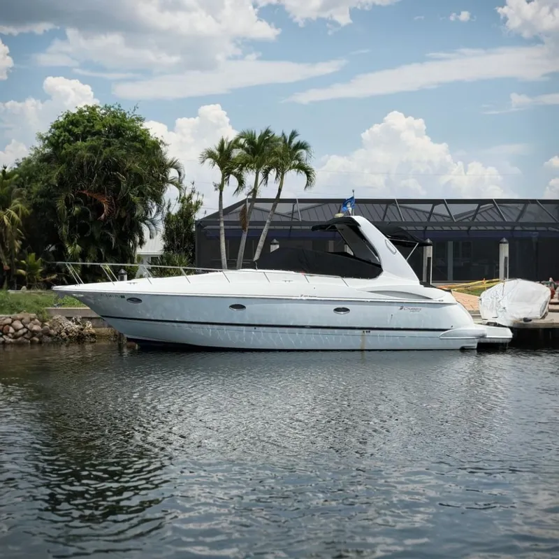 The Image of 2001 Cruisers Yachts 3672 Express docked by palm trees and waterfront home. - 0