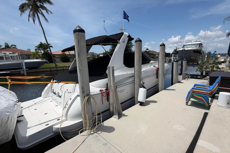 Slide: The Image of 2001 Cruisers Yachts 3672 Express docked at marina with colorful chairs nearby. - 3