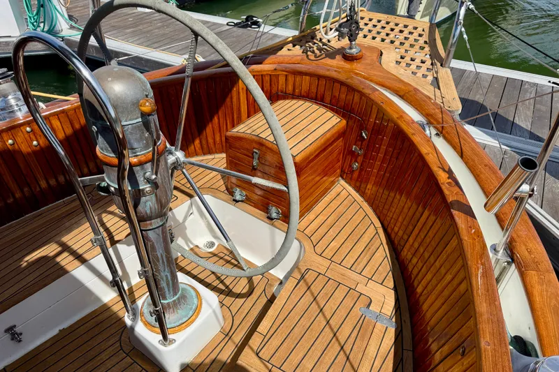 Slide: The Image of 1977 Hans Christian Ketch sailboat cockpit with wooden details and steering wheel. - 10