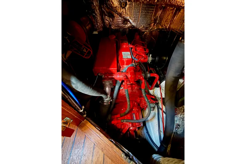 Slide: The Image of Engine compartment of a 1977 Hans Christian Ketch sailboat, featuring a red engine. - 70