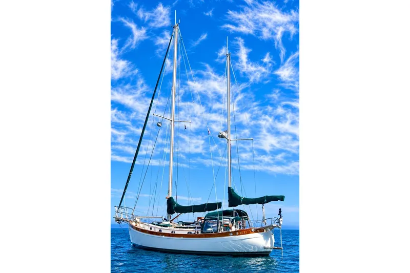 Slide: The Image of 1977 Hans Christian Ketch sailboat on calm ocean under vibrant blue sky. - 1