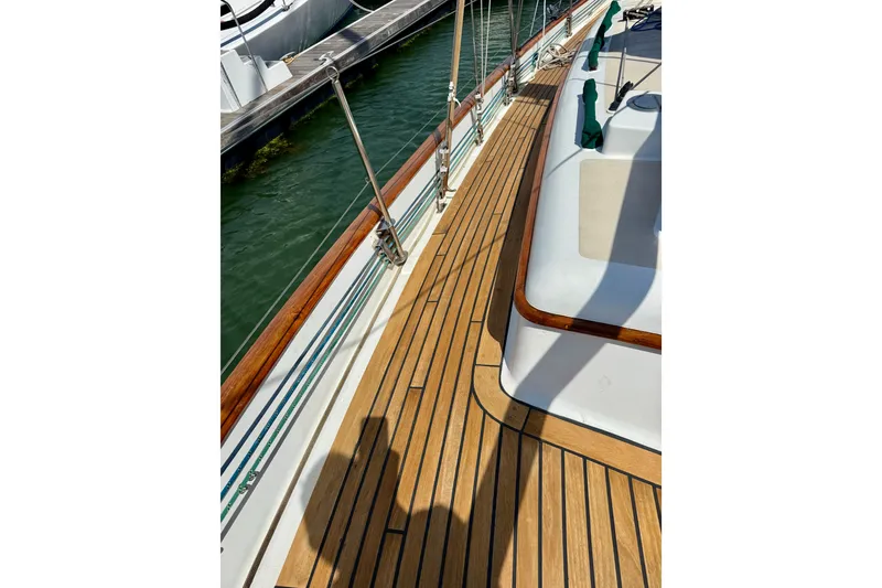 Slide: The Image of 1977 Hans Christian Ketch sailboat deck with teak wood finish, docked at marina. - 13