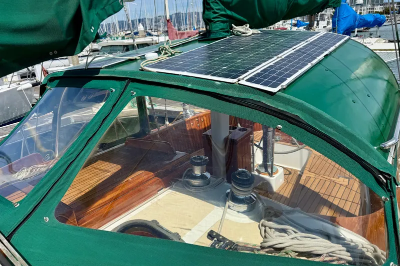 Slide: The Image of 1977 Hans Christian Ketch with solar panels, green canopy, and wooden deck at marina. - 17