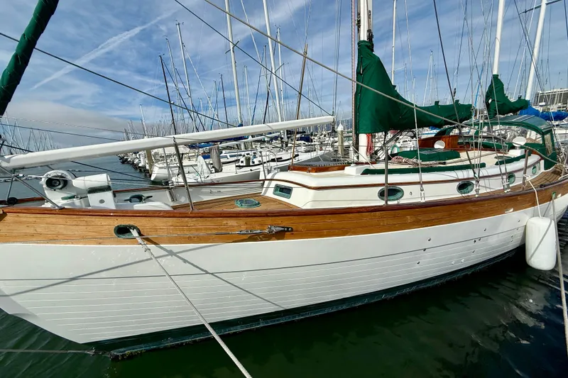 Slide: The Image of 1977 Hans Christian Ketch sailboat docked in a marina, featuring classic wooden design. - 5