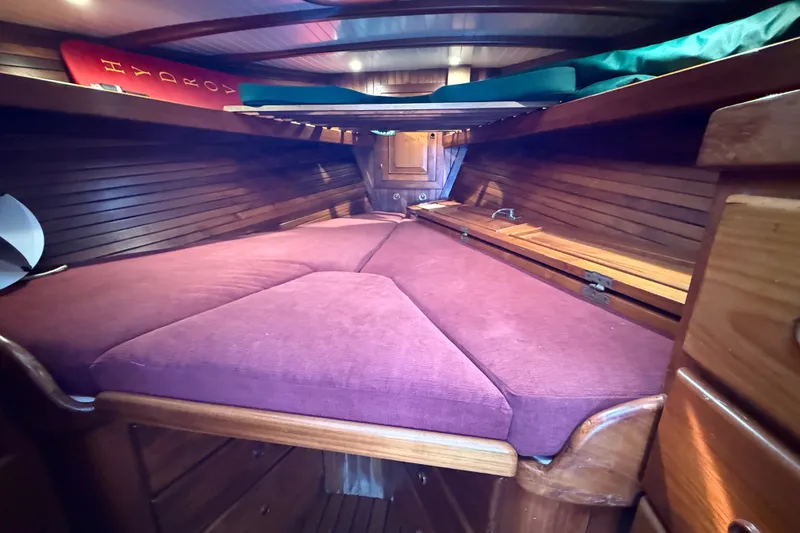 Slide: The Image of Cozy cabin interior of a 1977 Hans Christian Ketch sailboat with wooden finish and purple cushions. - 45