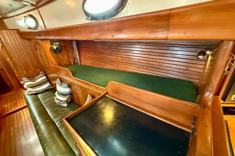Slide: The Image of 1977 Hans Christian Ketch interior with wooden finish, green cushion, and striped pillows. - 43