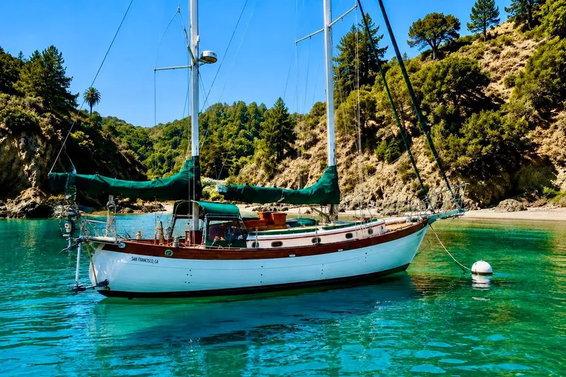 Slide: The Image of Classic 1977 Hans Christian Ketch sailboat anchored in a serene, turquoise bay. - 4