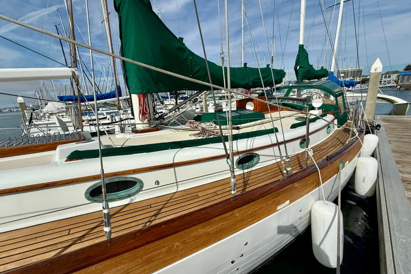 Slide: The Image of 1977 Hans Christian Ketch sailboat docked, featuring wooden deck and green sail covers. - 6