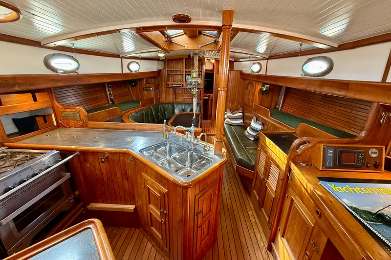 Slide: The Image of 1977 Hans Christian Ketch interior with wooden cabinetry, kitchen, and seating area. - 22