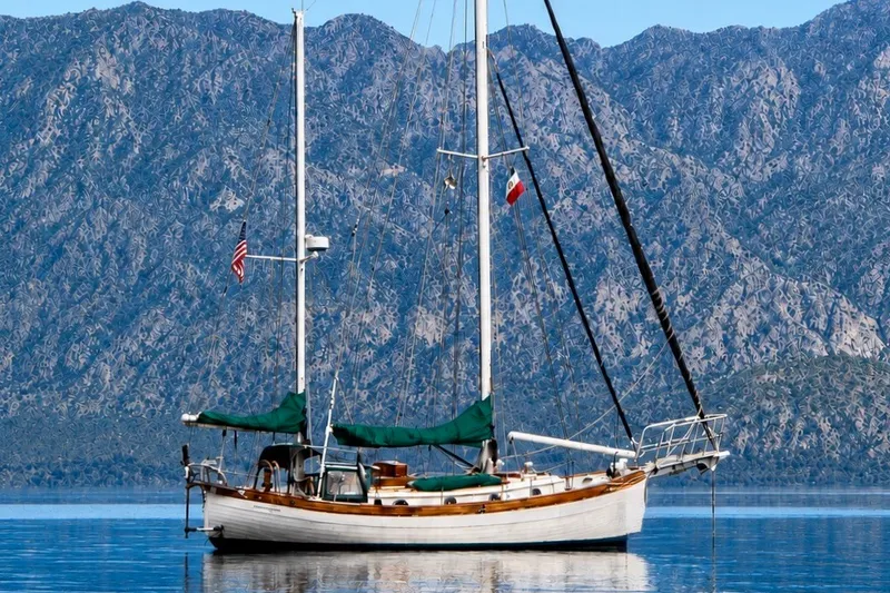 Slide: The Image of Sailboat "Hans Christian Ketch" 1977 on calm water with mountainous backdrop. - 3