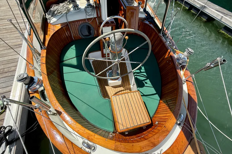 Slide: The Image of 1977 Hans Christian Ketch sailboat cockpit with wooden accents and green cushions. - 18