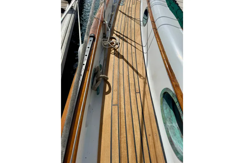 Slide: The Image of Wooden deck of a 1977 Hans Christian Ketch sailboat, featuring ropes and portholes. - 15