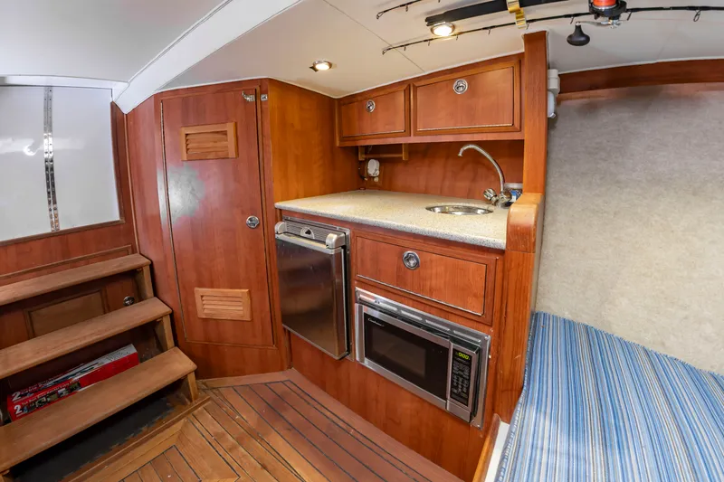 Slide: The Image of The cabin of the 2006 Custom Carolina 36 Express features a compact kitchen with wooden cabinets. - 32