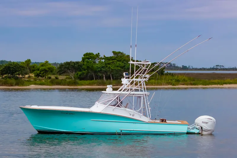 The Image of A 2006 Custom Carolina 36 Express with a turquoise hull, anchored on calm water. - 0