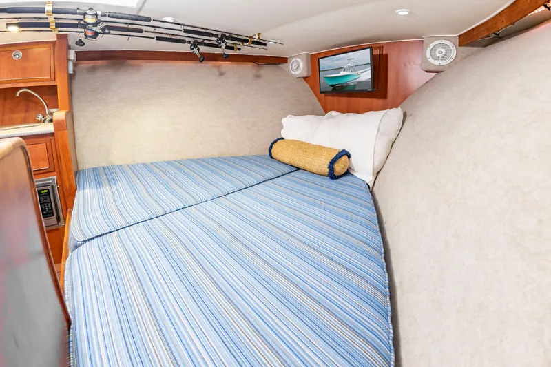 Slide: The Image of The cabin of the 2006 Custom Carolina 36 Express features a cozy bed with blue bedding. - 40