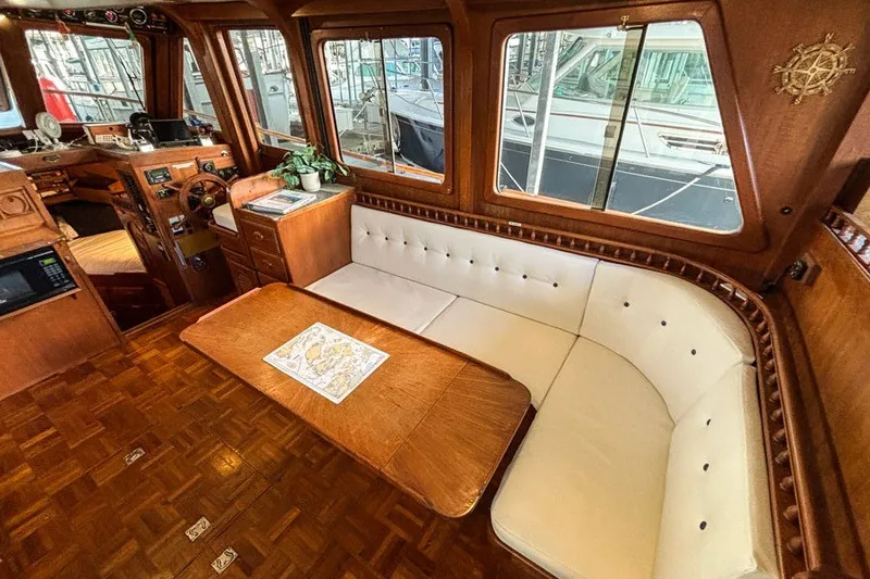 Slide: The Image of 1979 Hershine San Francisco yacht interior with wooden decor, white seating, and navigation area. - 3