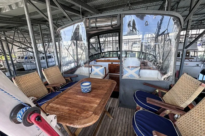 Slide: The Image of 1979 Hershine San Francisco yacht interior with wooden table, wicker chairs, and clear canopy. - 12