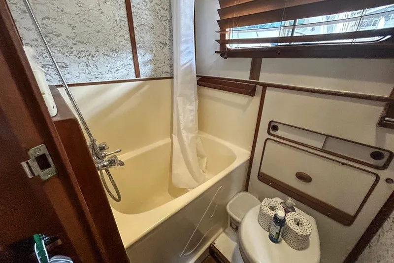 Slide: The Image of 1979 Hershine San Francisco yacht bathroom with bathtub, shower, and wooden accents. - 14
