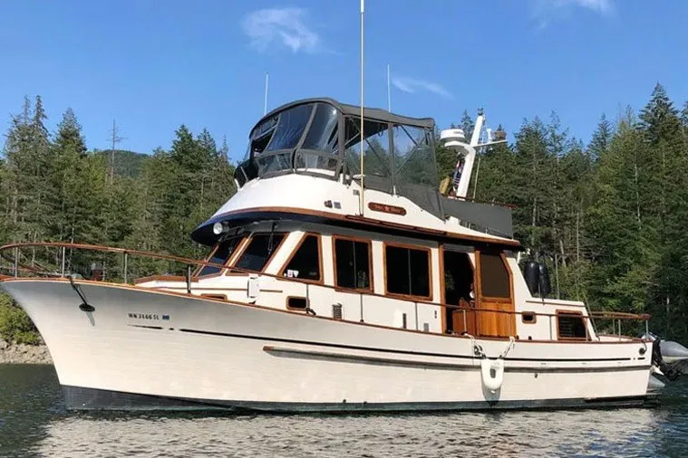 The Image of Classic 1979 Hershine San Francisco yacht on serene water, surrounded by lush trees. - 0