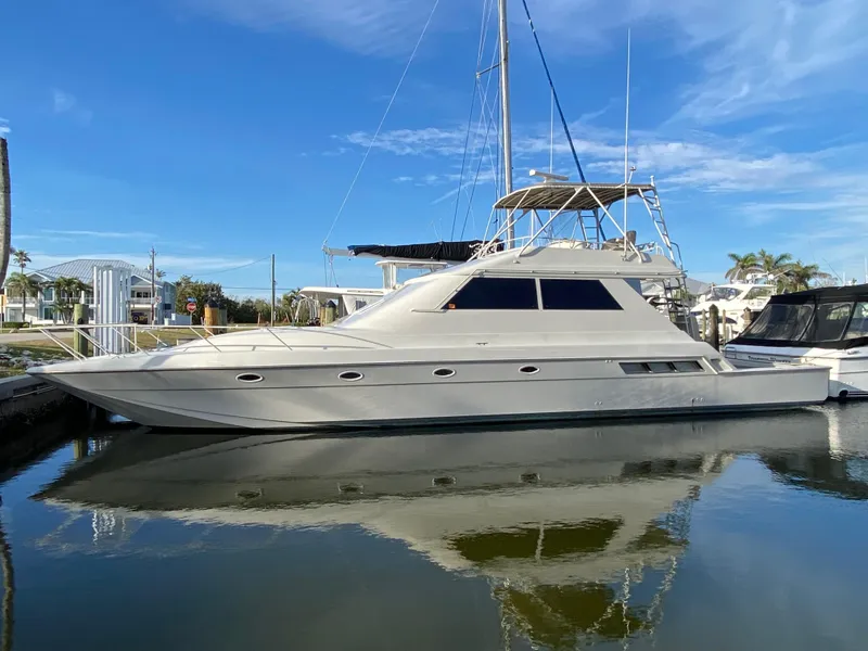 Slide: The Image of 1995 Mares 58 Power Catamaran docked, reflecting on calm water under a clear blue sky. - 2