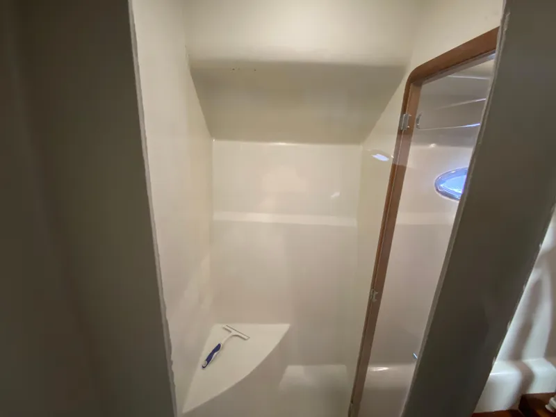Slide: The Image of Shower area inside a 1995 Mares 58 Power Cat, featuring a glass door and white interior. - 52
