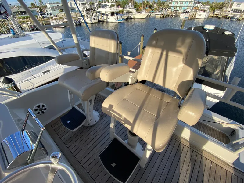 Slide: The Image of Two beige captain chairs on a 1995 Mares 58 Power Cat, docked at a marina. - 15