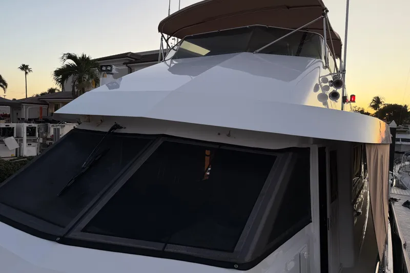 Slide: The Image of 1991 Hatteras 70 Motor Yacht at sunset, docked with palm trees in the background. - 27