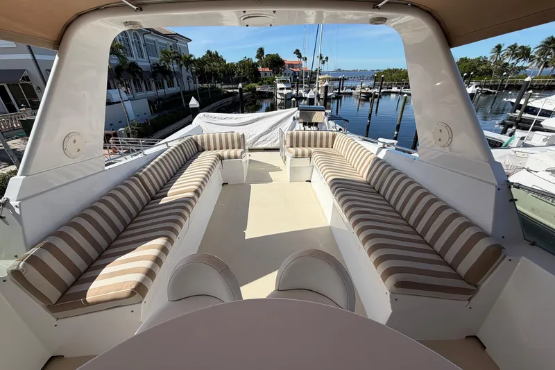 Slide: The Image of 1991 Hatteras 70 Motor Yacht deck with striped seating, docked at marina. - 48
