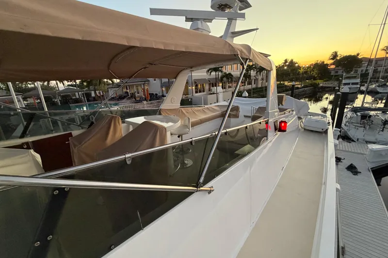 Slide: The Image of 1991 Hatteras 70 Motor Yacht docked at sunset, featuring covered seating and sleek design. - 25