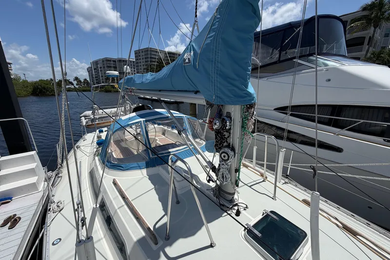 Slide: The Image of 1987 Moody 376 sailboat docked, featuring blue sail cover and spacious deck. - 12
