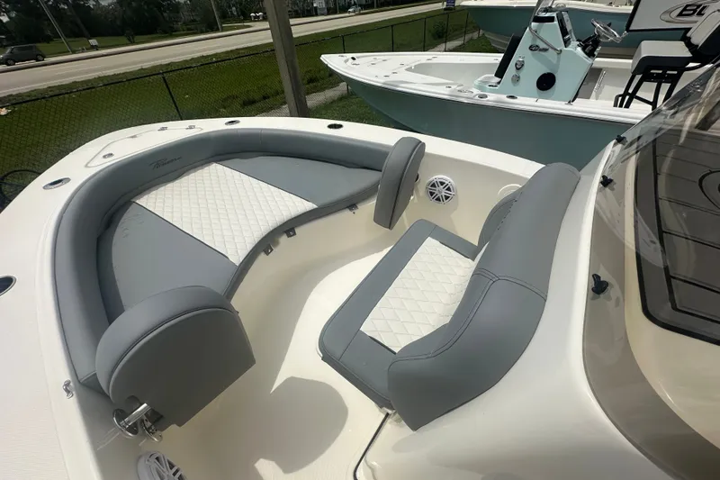 Slide: The Image of 2027 Pioneer 180 Islander boat interior with gray and white seating, docked outdoors. - 5