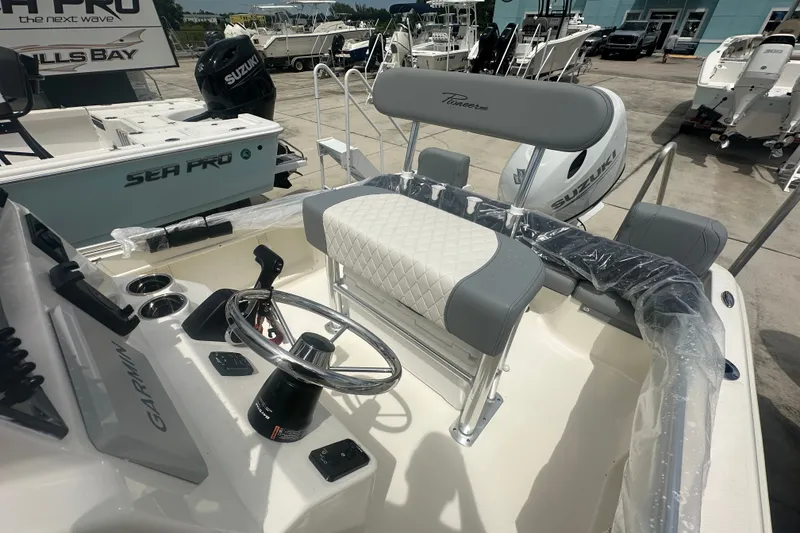 Slide: The Image of 2027 Pioneer 180 Islander boat interior with steering wheel and seating, featuring Suzuki engine. - 8
