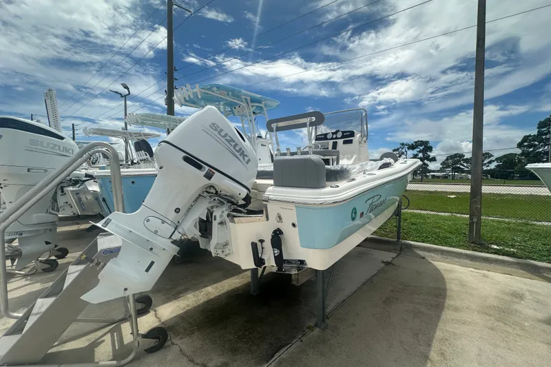 Slide: The Image of 2027 Pioneer 180 Islander boat with Suzuki outboard motor, displayed outdoors under a cloudy sky. - 2