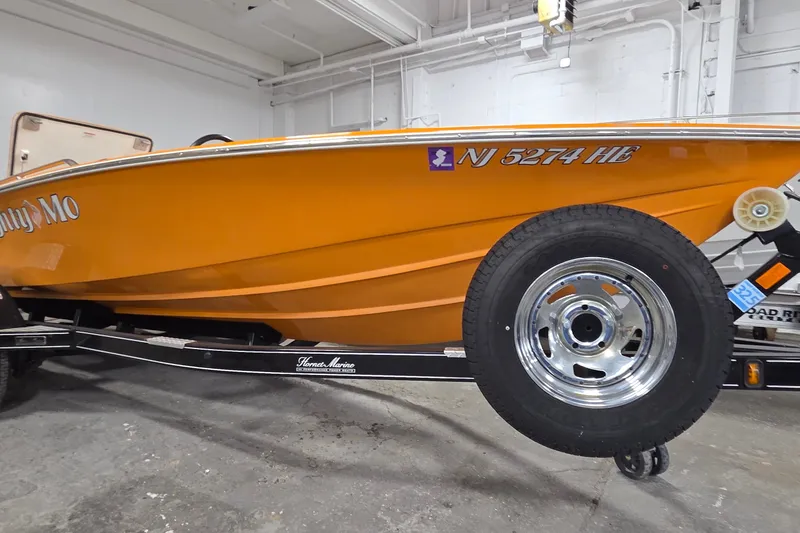 Slide: The Image of Orange 2012 Hornet Marine 17 boat on trailer, displayed indoors. - 31