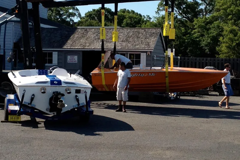 Slide: The Image of 2012 Hornet Marine 17 boat being lifted at a marina with people nearby. - 35