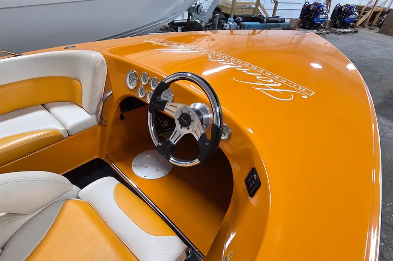 Slide: The Image of 2012 Hornet Marine 17 boat interior with orange and white seating, steering wheel, and dashboard. - 9