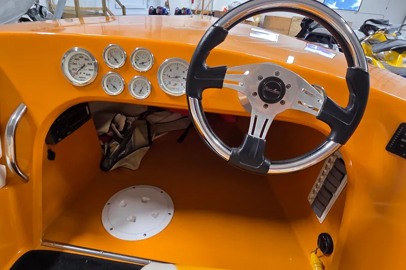 Slide: The Image of Orange dashboard of a 2012 Hornet Marine 17 boat with gauges and steering wheel. - 26