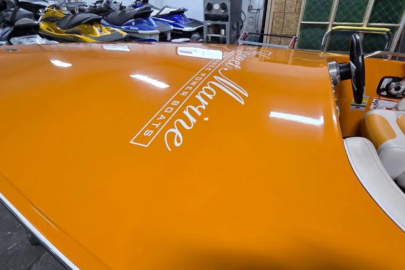 Slide: The Image of Orange 2012 Hornet Marine 17 powerboat with sleek design and logo in a showroom. - 16
