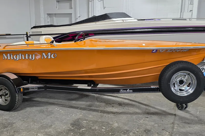 Slide: The Image of Orange 2012 Hornet Marine 17 boat named "Mighty Mo" on a trailer in a garage. - 2
