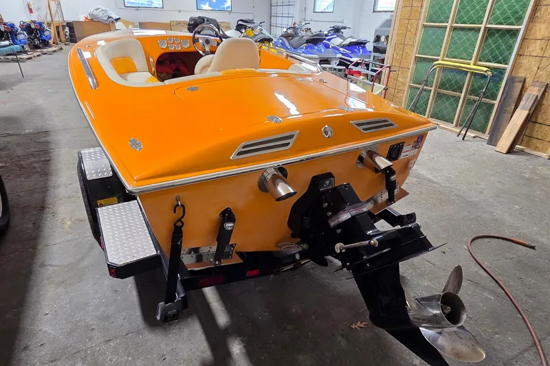 Slide: The Image of Orange 2012 Hornet Marine 17 boat in a garage, showcasing rear view and propeller. - 10