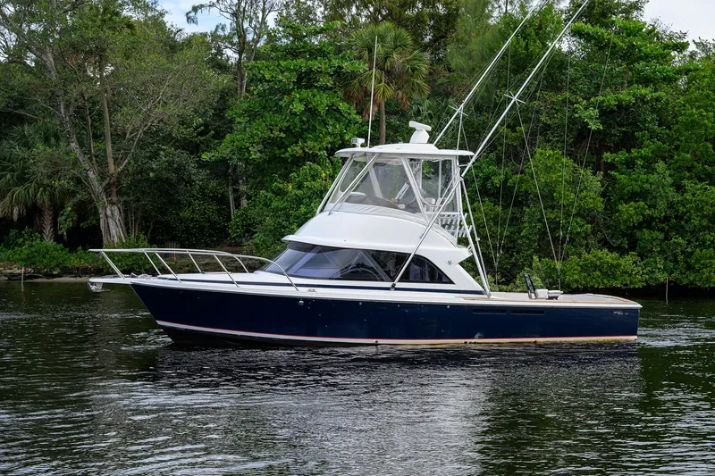 Slide: The Image of 2018 Bertram 35 Flybridge boat on calm water, surrounded by lush greenery. - 8