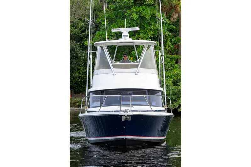Slide: The Image of 2018 Bertram 35 Flybridge boat on water, surrounded by lush greenery. - 4