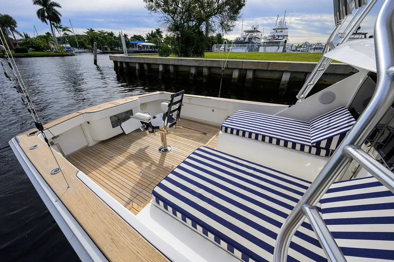 Slide: The Image of 2018 Bertram 35 Flybridge boat with striped seating, docked by a scenic waterfront. - 20