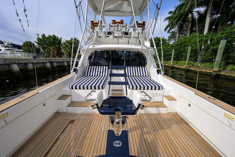 Slide: The Image of 2018 Bertram 35 Flybridge yacht with striped seating, docked by lush greenery. - 15