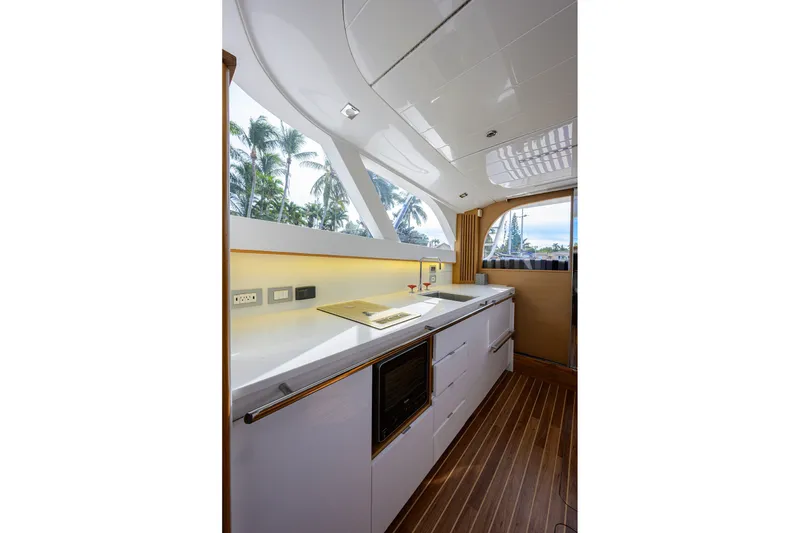 Slide: The Image of Modern kitchen interior of 2018 Bertram 35 Flybridge yacht with sleek design and palm tree view. - 35