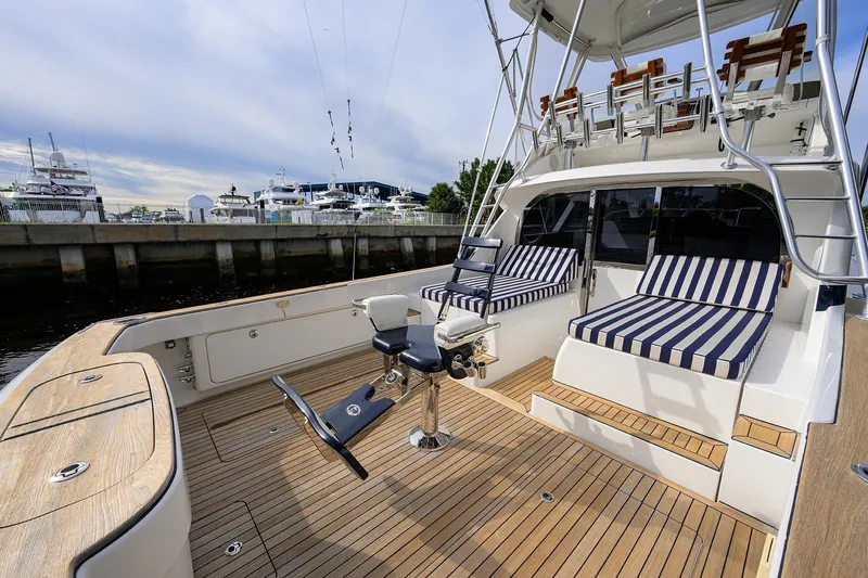 Slide: The Image of 2018 Bertram 35 Flybridge yacht with striped seating and fishing chair at marina. - 14