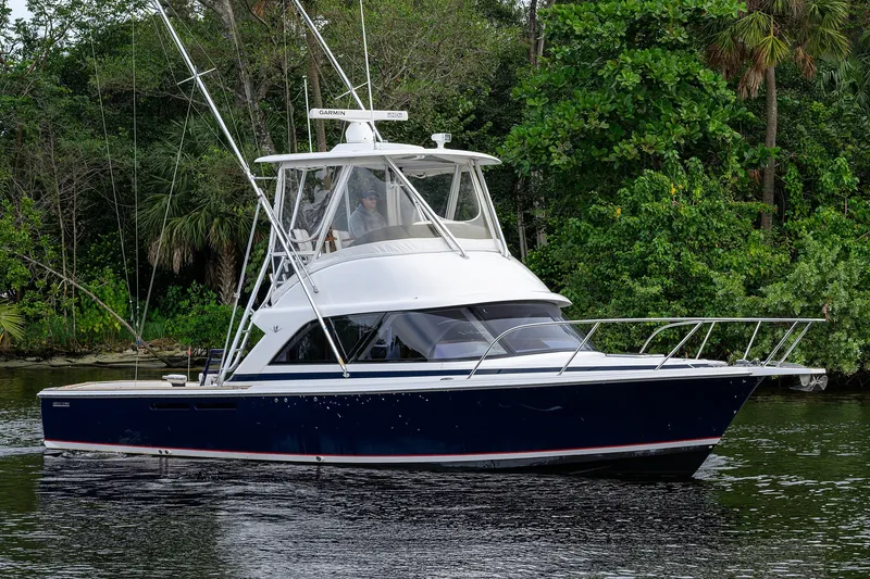 Slide: The Image of 2018 Bertram 35 Flybridge yacht cruising on a serene waterway, surrounded by lush greenery. - 6