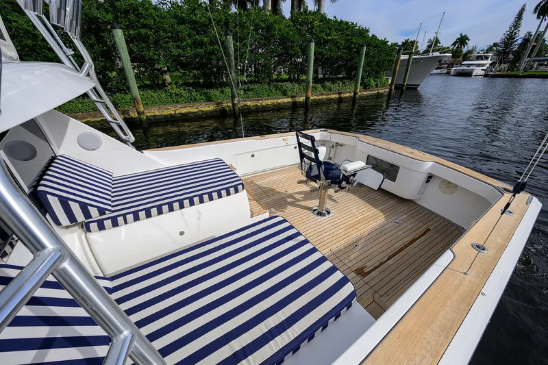 Slide: The Image of 2018 Bertram 35 Flybridge boat with striped seating and wooden deck by the water. - 18